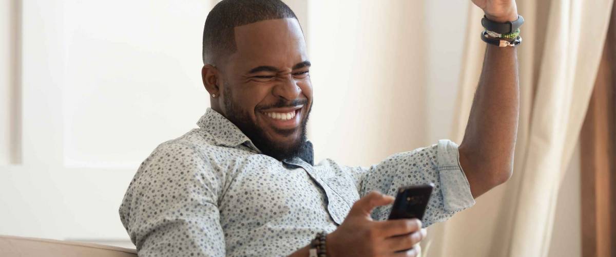 Overjoyed black man winner holding smartphone