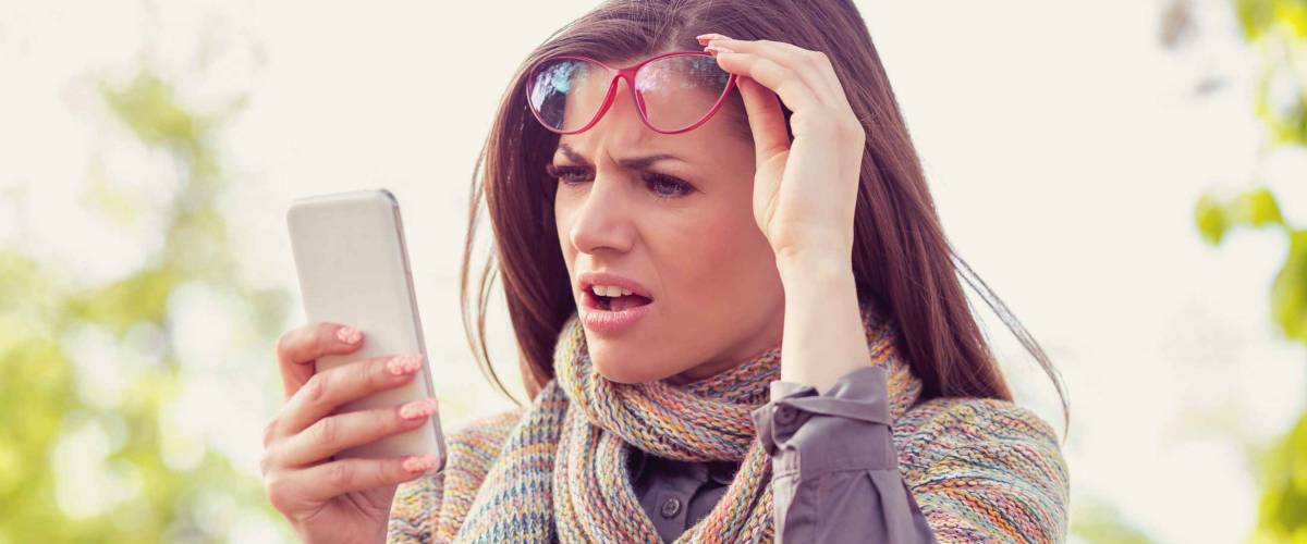 Annoyed upset woman in glasses looking at her smart phone