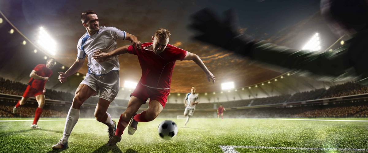Soccer players in action on the sunset stadium background panorama