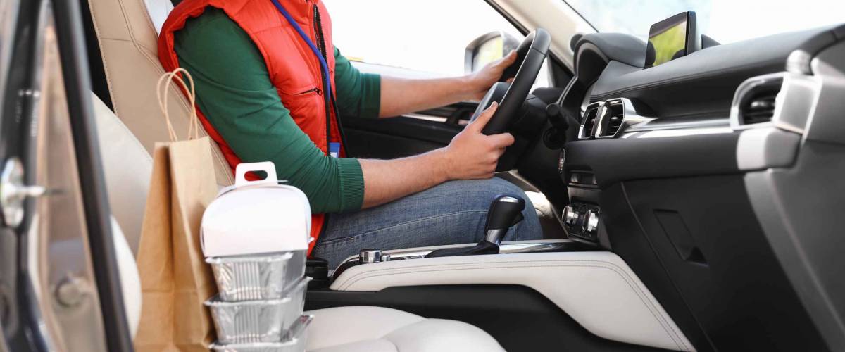 Male courier with orders in car. Food delivery service