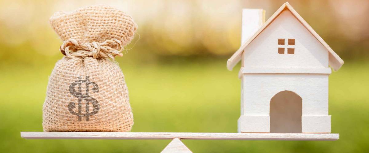Home and money bag put on the scales with balance put on the wood in the public park, Saving for buy a new house or real estate and loan for plan business investment in the future concept.