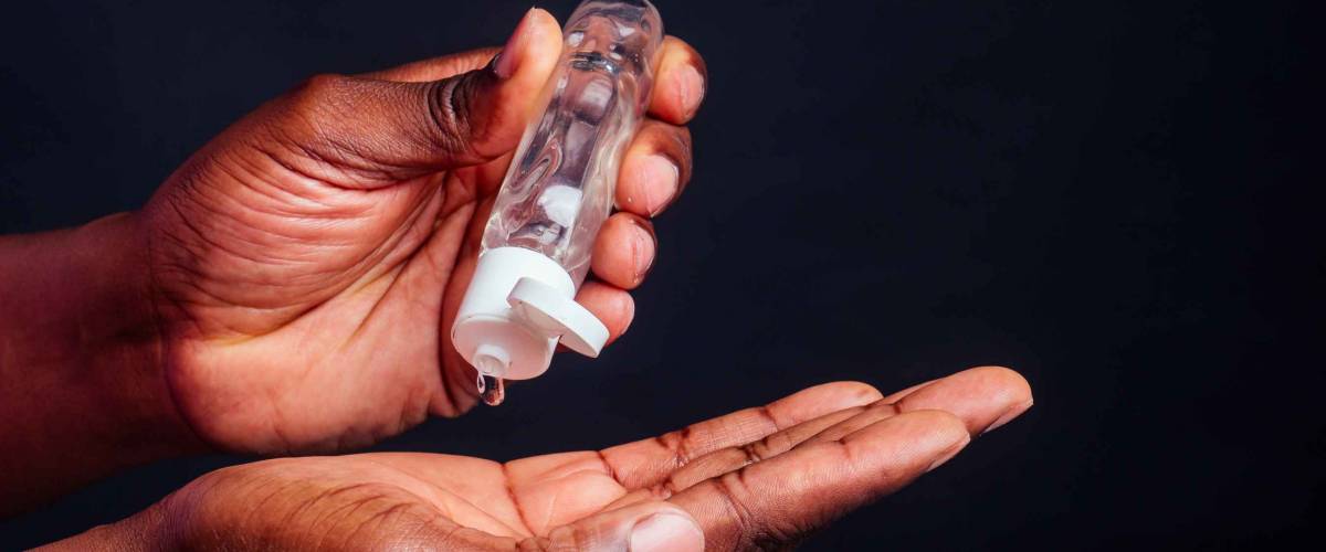 close up hands of afro male useing antiseptic in studio black background.