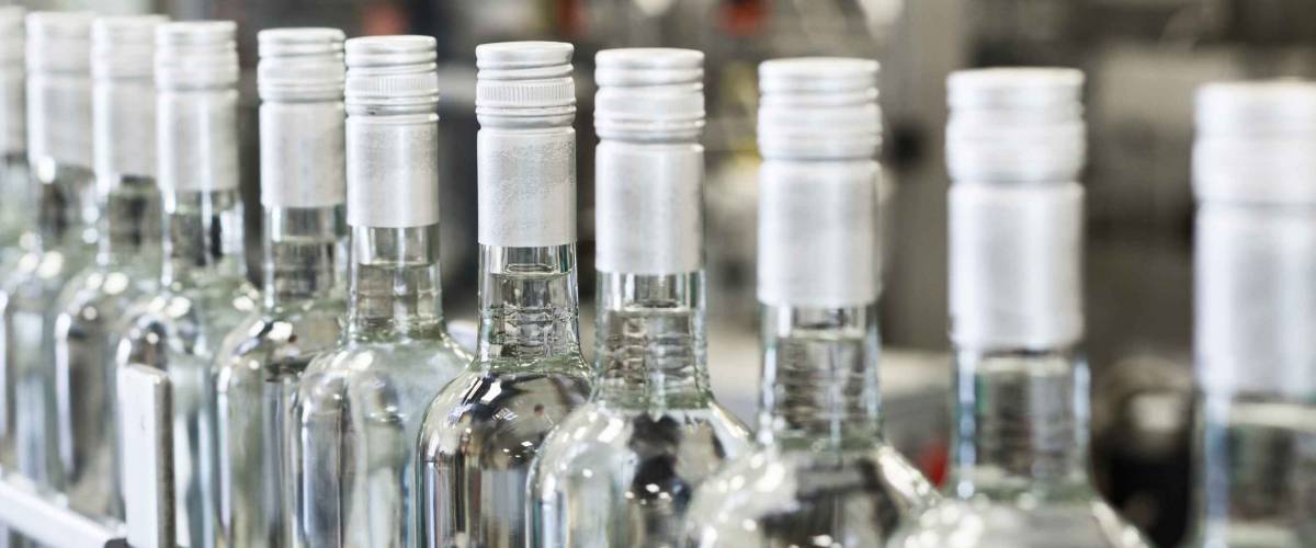 A long row of glass bottles on the conveyor. Manufacture of alcoholic beverages.