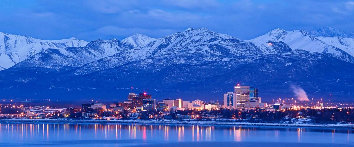 Anchorage Alaska skyline in winter at dusk with the Chugach mountains behind.