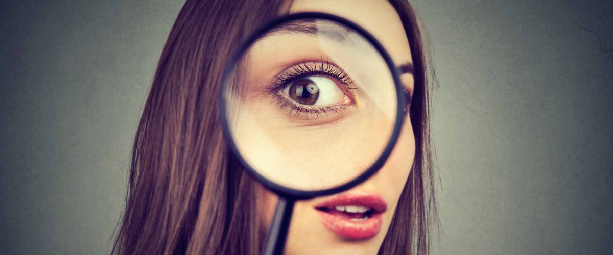 Curious woman looking through a magnifying glass