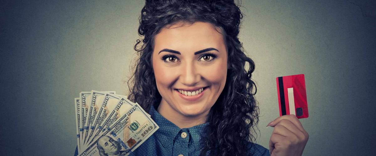 Young woman shopping holding showing credit card and cash dollar banknotes bills
