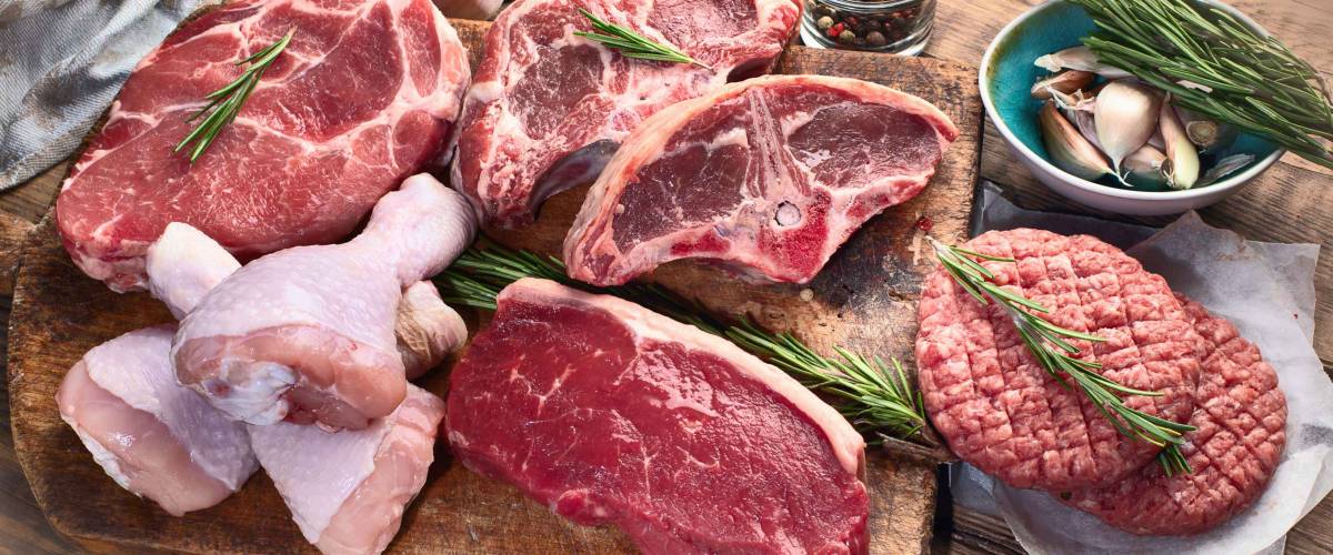 Different types of raw meat - beef, pork, lamb, chicken on a wooden board.