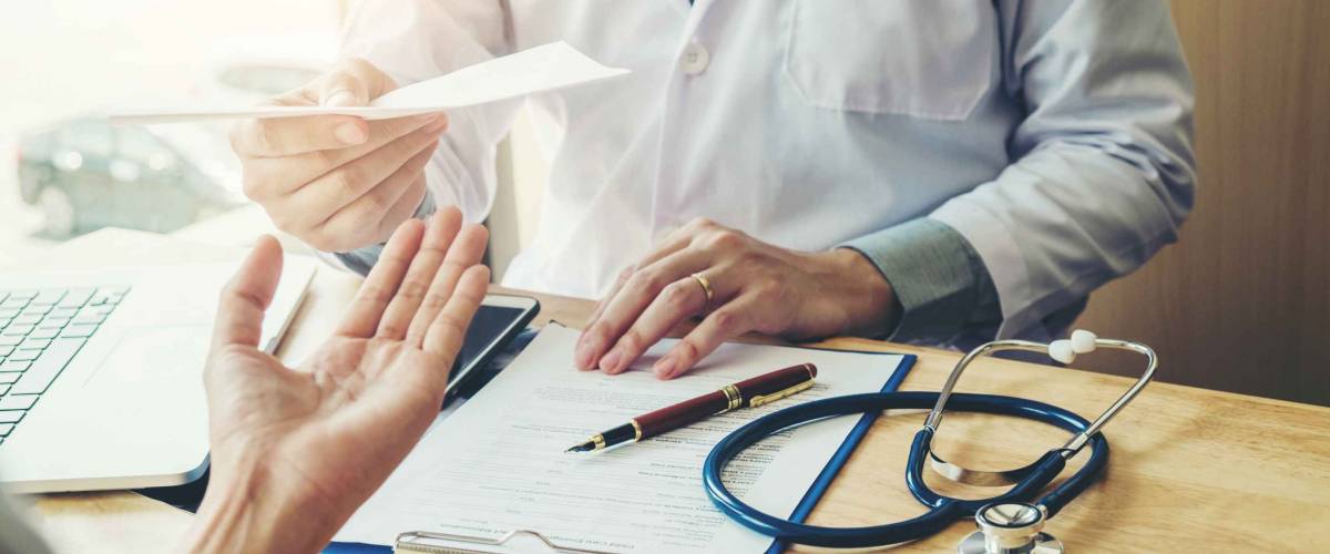 Doctor or physician writing diagnosis and giving a medical prescription to female patient
