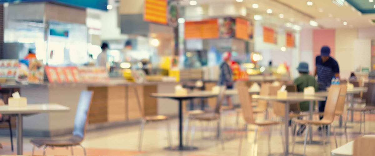 Defocused or blurred photo of food court and wood table top use for background.