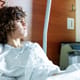 Young boy in a hospital bed looking sad and off to the side.