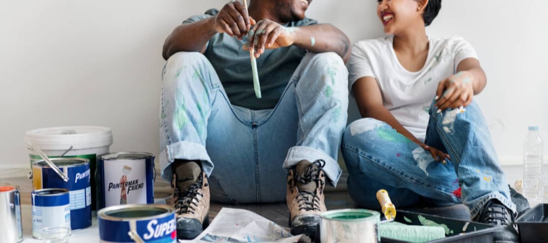 Man and woman taking a pause from painting inside a home