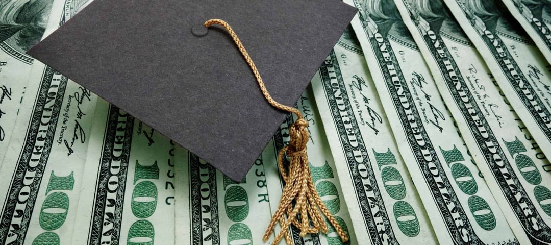 graduation cap on assorted hundred dollar bills - education concept