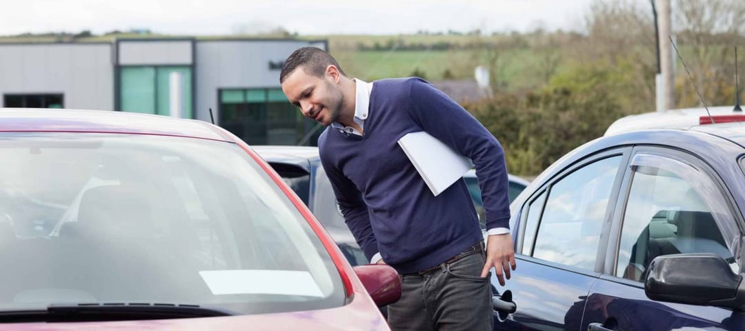 Man looking at a car while leaning outdoors