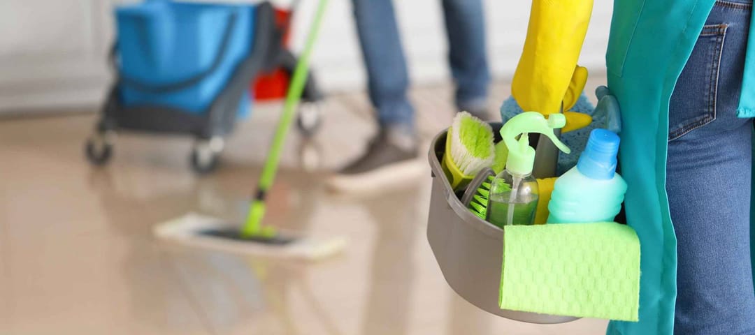 Female janitor with cleaning supplies in kitchen