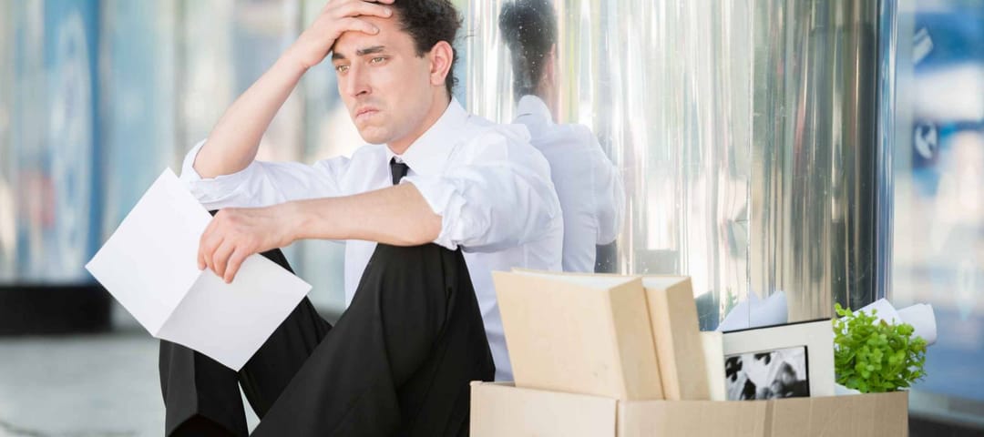Fired frustrated man in suit sitting near office.
