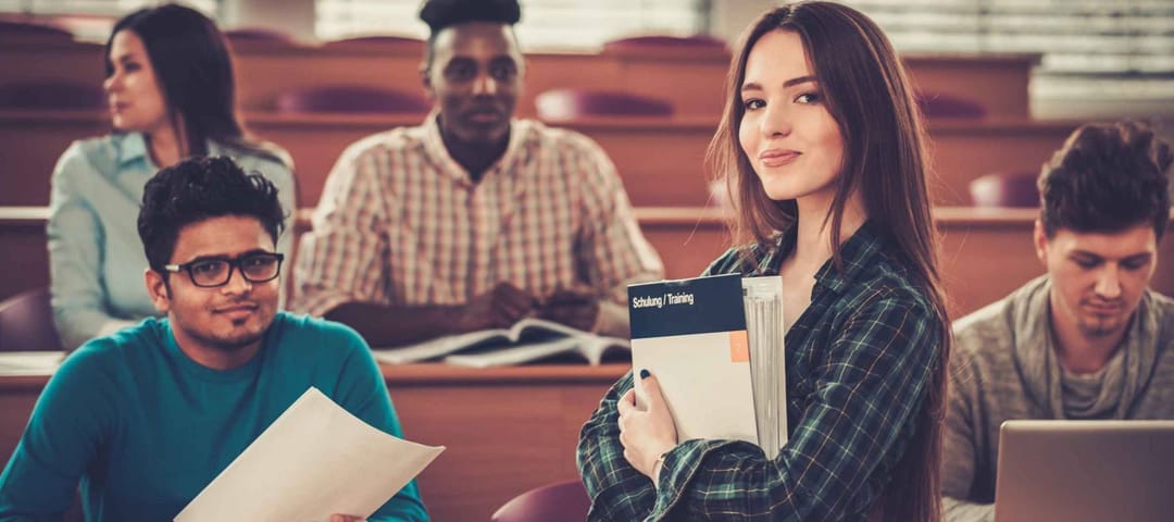 Multinational group of cheerful students taking an active part in a lesson while sitting in a lecture hall.