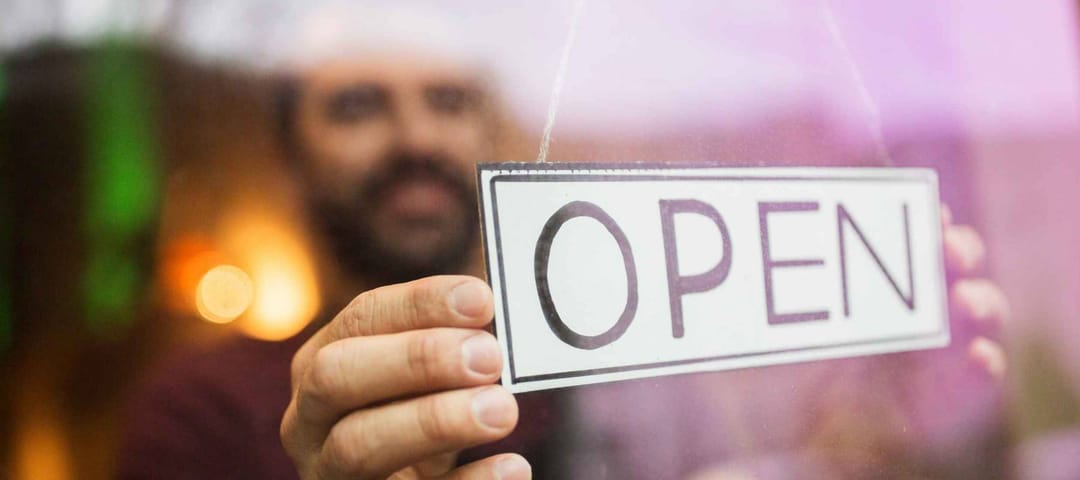 small business, people and service concept - man with open word on banner at bar or restaurant window