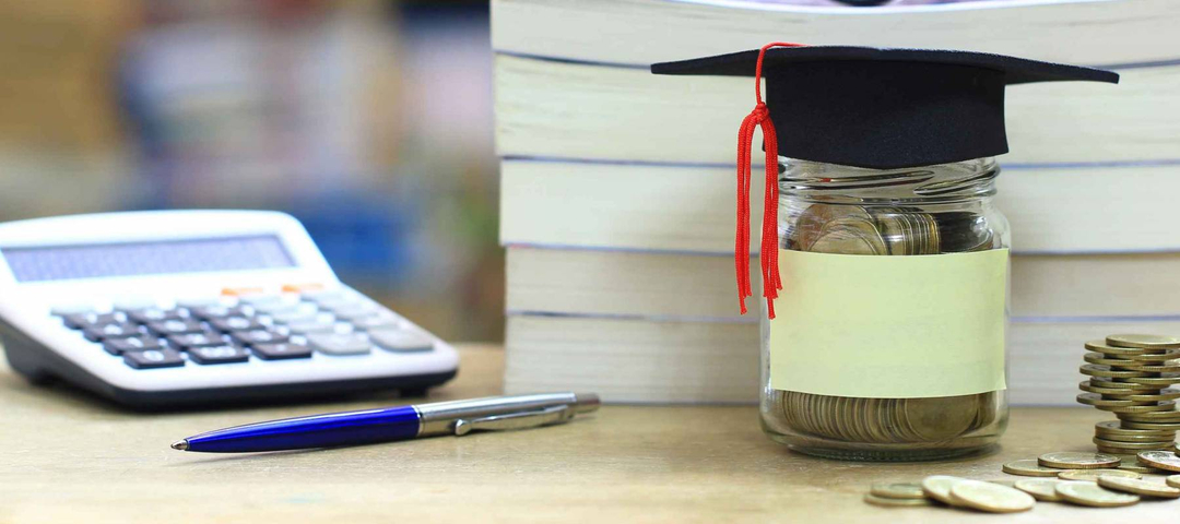 Graduation hat on the glass bottle on bookshelf in the library room background, Saving money for education concept