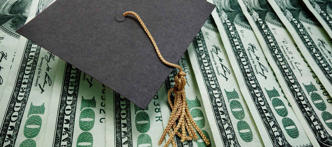 graduation cap on assorted hundred dollar bills - education concept