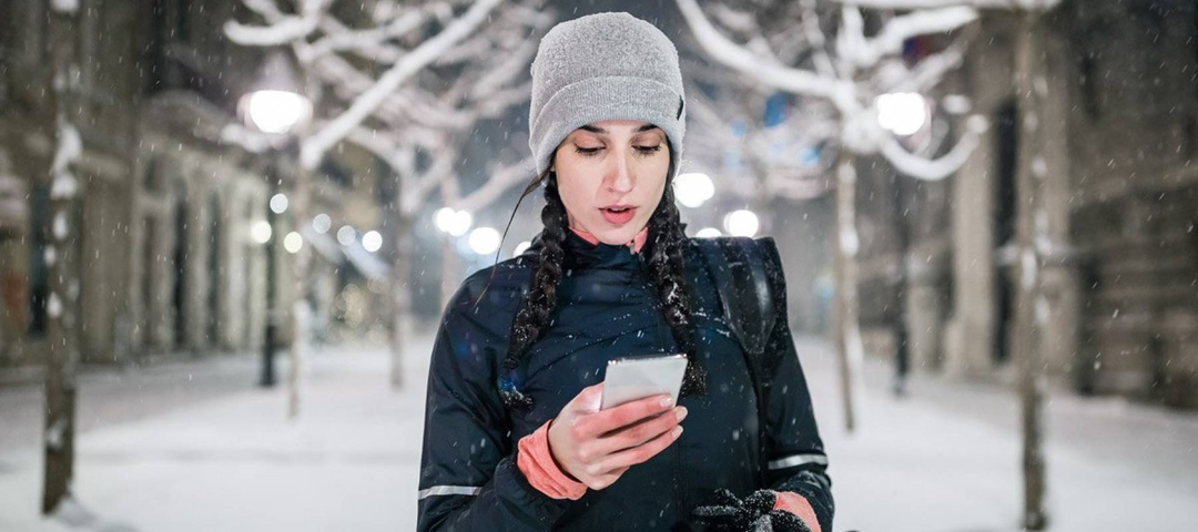 Woman checks her credit score on her smartphone while a light snow falls