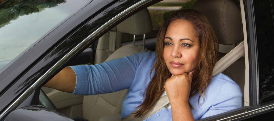 Woman sitting in her car daydreaming.