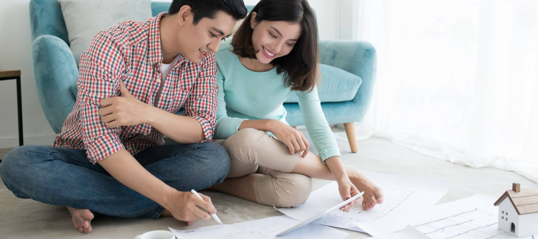 Attractive young asian adult couple looking at house plans.