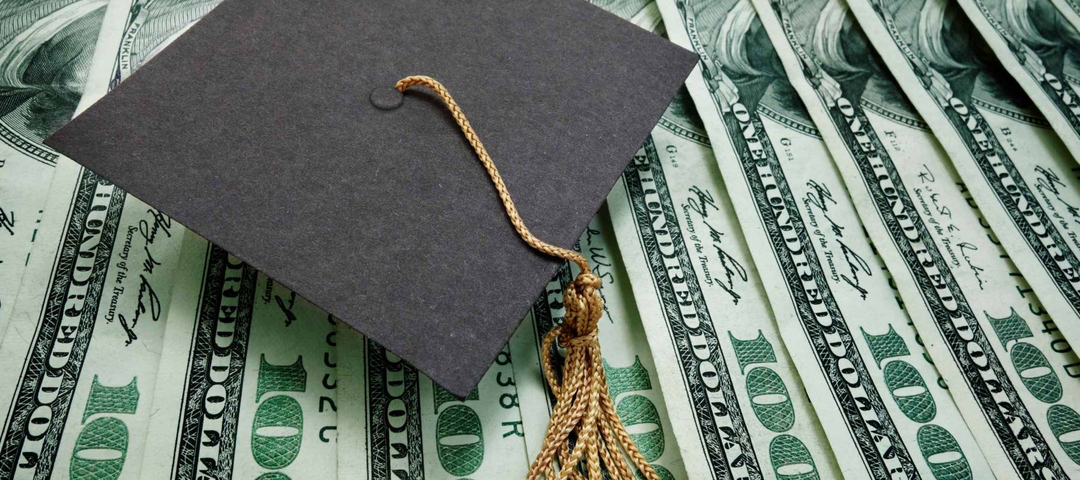graduation cap on assorted hundred dollar bills - education concept