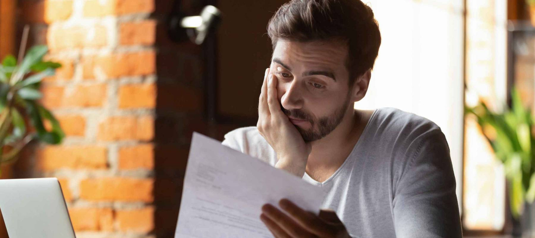 Confused and concerned young man reviewing student loan statement