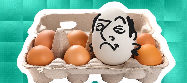 Smug looking egg with a cartoon face sits in an egg carton.