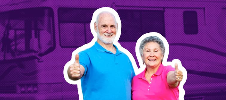 Older couple poses with their thumbs up in front of an RV.