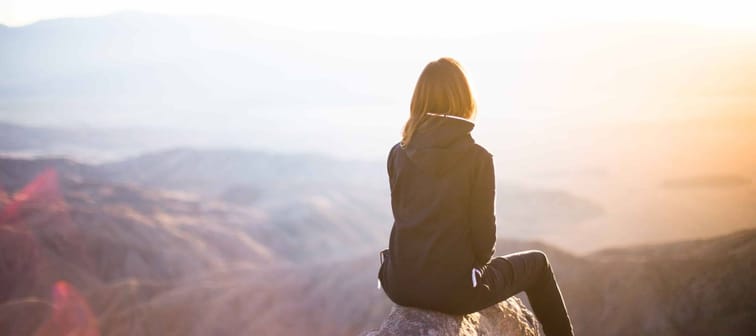 Woman sitting on mountain top making long term financial goals after paying off all her debt