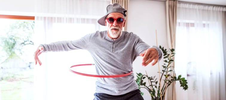 Senior man with hula hoop having fun at home.