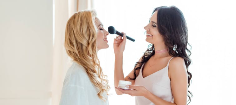 beautiful young bride getting makeup from bridesmaid before wedding