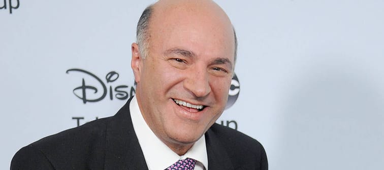 Kevin O'Leary smiles in front of a Disney backdrop.