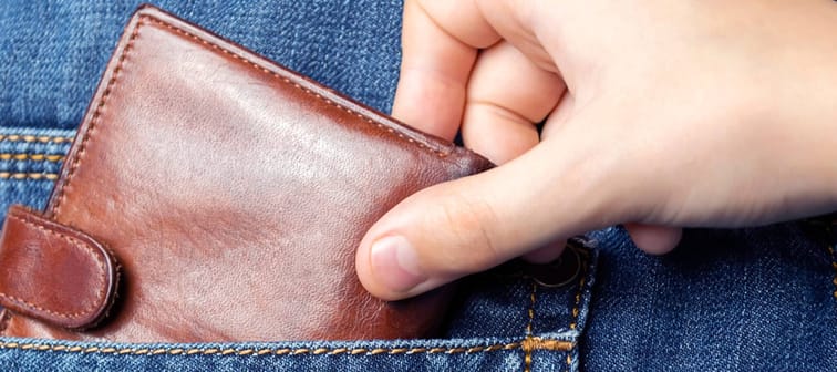 a hand pickpocketing a wallet from the back of someone's jeans