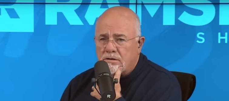 Dave Ramsey sitting on set of his radio show, with his hand on his chin looking concerned.