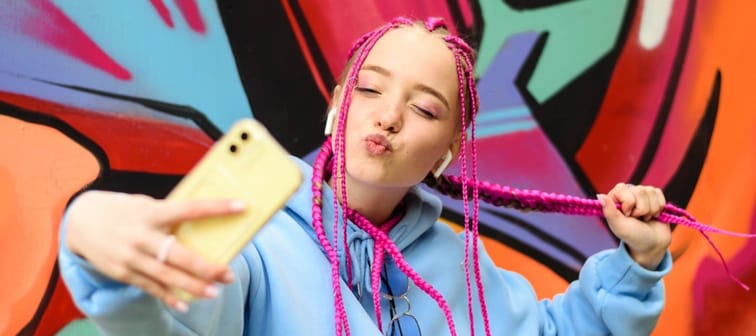 young Gen Z woman with bright pink hair poses for a selfie