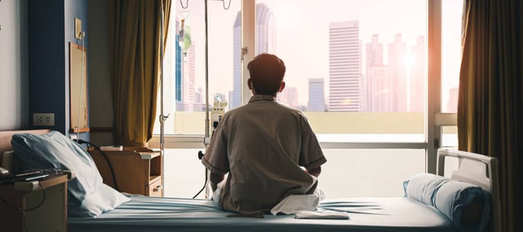 patient sat on the bed and looked out the window in the hospital alone