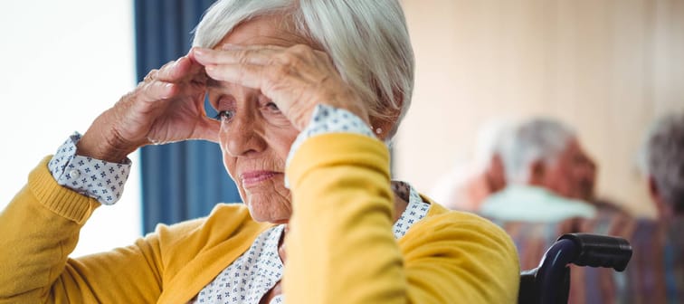 Senior woman in wheelchair look worried with her hands on her forehead