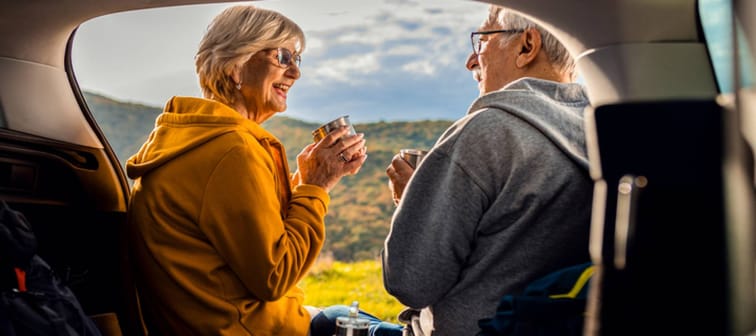 Older adult couple smile from back of SUV enjoying the West Virginia landscape.