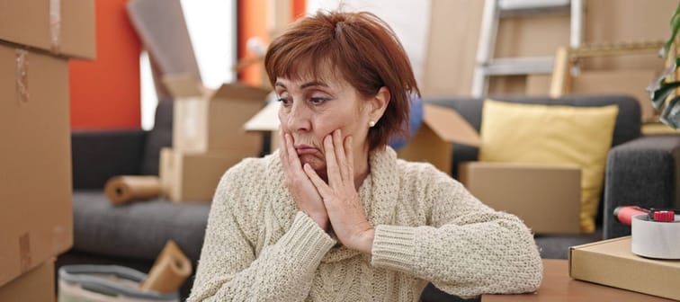 woman sitting on the floor looking around tired at new home