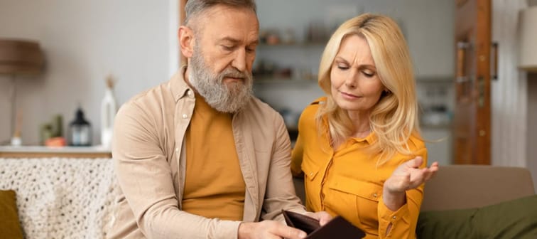 Older couple look at empty wallet.