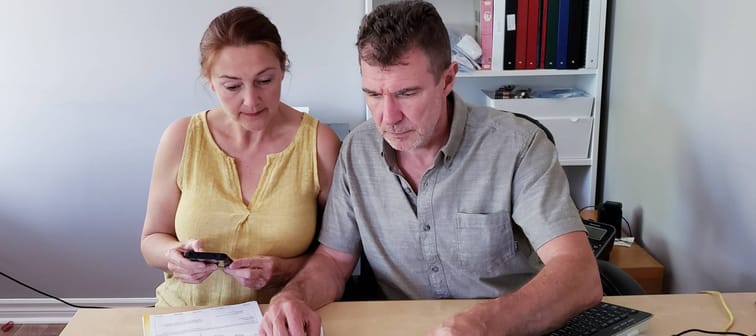 Couple look at documents laid out on a desk.