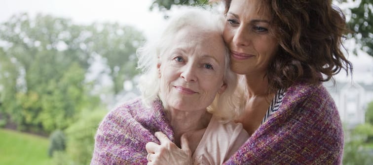 An older and younger woman share a tender moment.