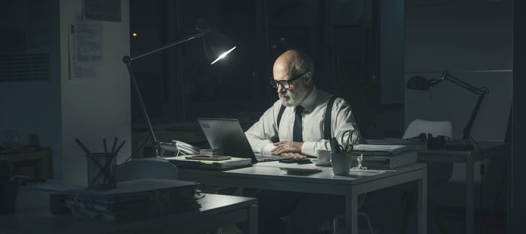 Corporate businessman working late at night in the office, he is connecting with his laptop.