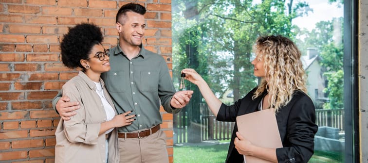 A couple gets the keys to their new home from a real estate agent.