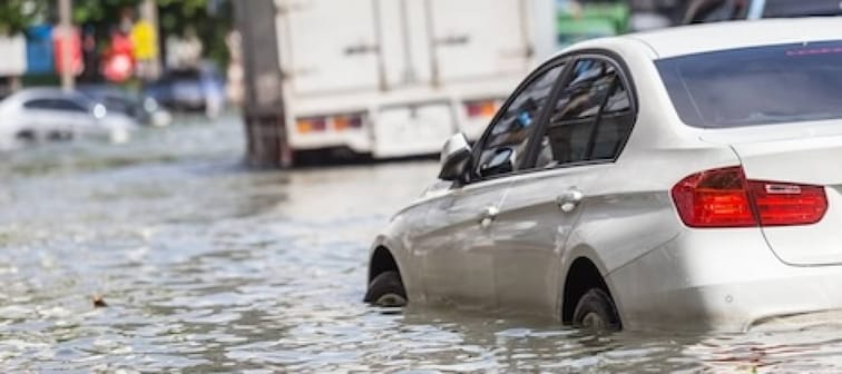 white car flooded in the street behind a flooded truck