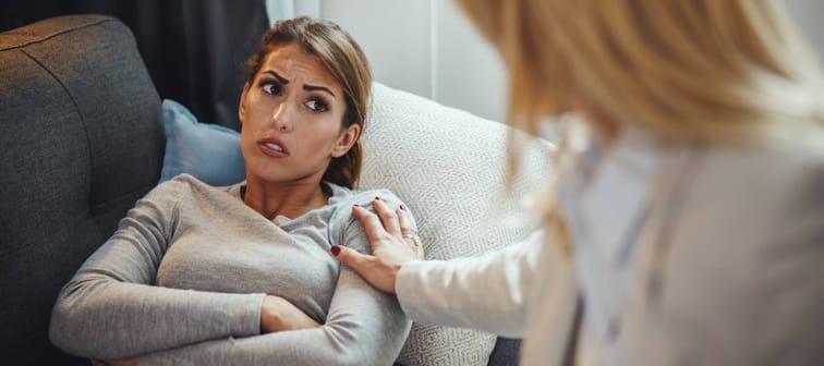 woman touching woman's shoulder on the couch