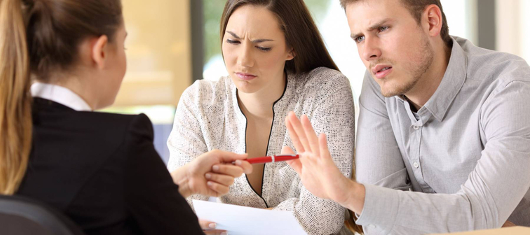 Bank adviser offering a pen to a couple of angry customers