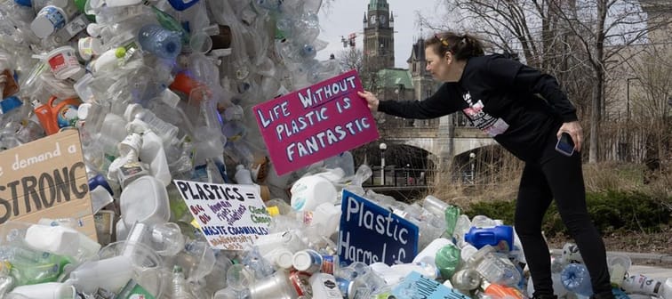 Activist Dianne Peterson places a sign on a public art installation outside a United Nations conference on plastics, Tuesday, April 23, 2024 in Ottawa. 